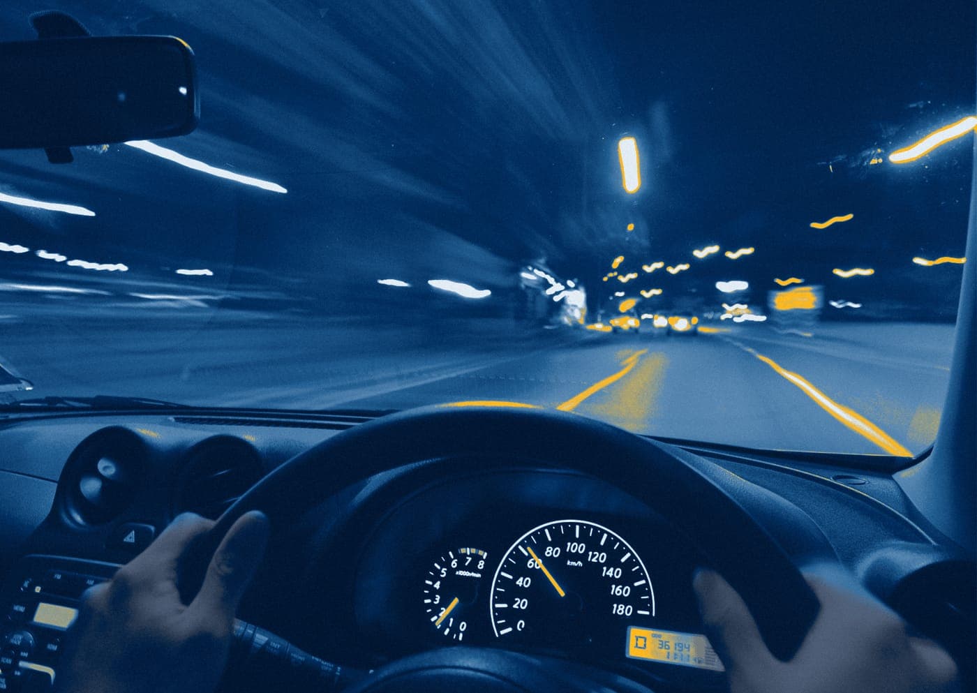 Driver view of a fleet vehicle on a night road, hands on the wheel