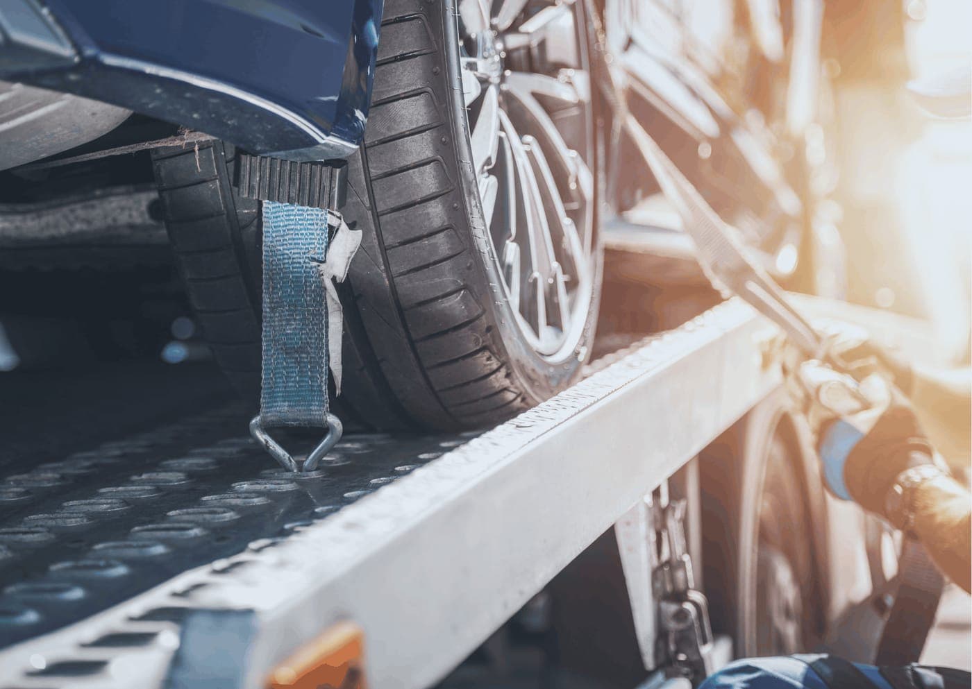 Damaged vehicle being strapped down on a tow truck tray after an accident